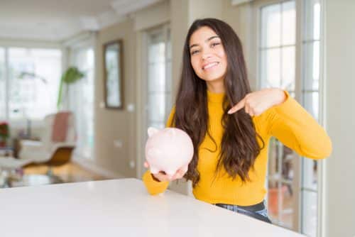 woman holding and pointing at a pink piggy bank