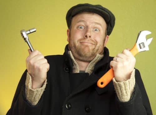 a man with a confused look holding a wrench and socket