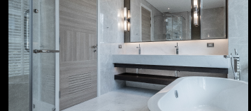 a modern and updated bathroom with a freestanding stone tub, and open glass shower, and two connected sinks with a large square mirror