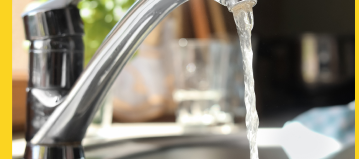 a silver kitchen faucet is turned on and water is streaming from the faucet