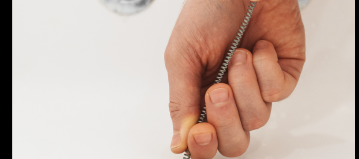 someone lowers a coiled tool into a drain in a bathtub