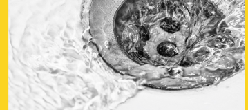 a close up of a small silver drain in a white sink with water flowing into it