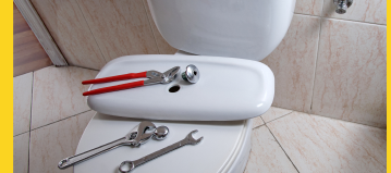 Toilet being repaired with tools on it