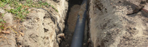 Installing sewer pipe in the ground trench. House sewer drain pipe installation