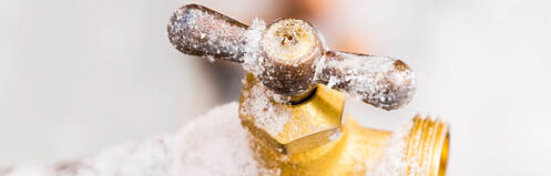 Frozen outdoor water faucet covered in snowflakes